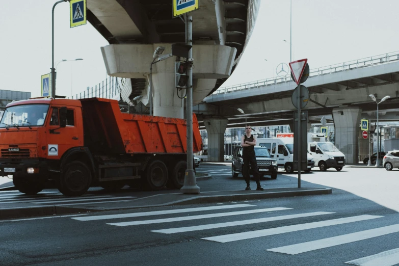 a red dump truck sitting on the side of a road, a photo, by Adam Marczyński, pexels contest winner, traffic police woman, overpass, standing in a city center, 🚿🗝📝