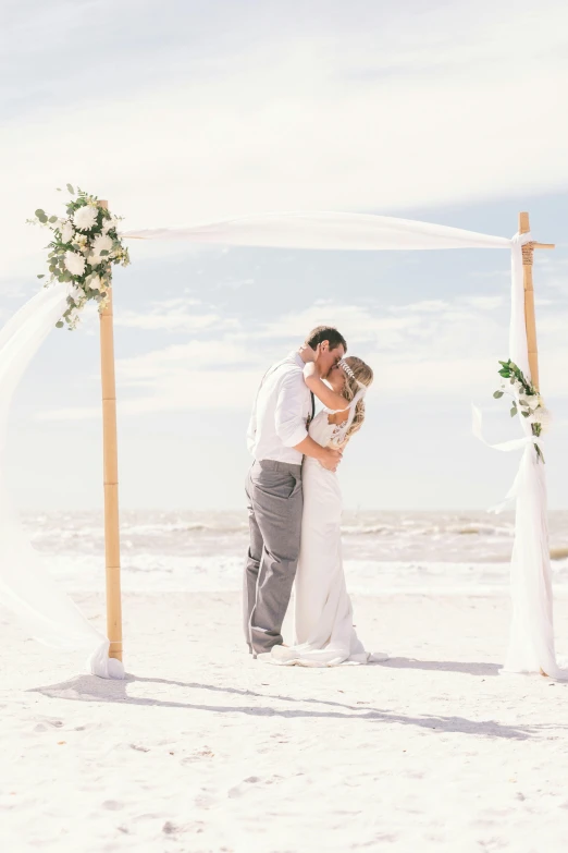 a bride and groom kissing on the beach, white sweeping arches, square, carson ellis, gulf