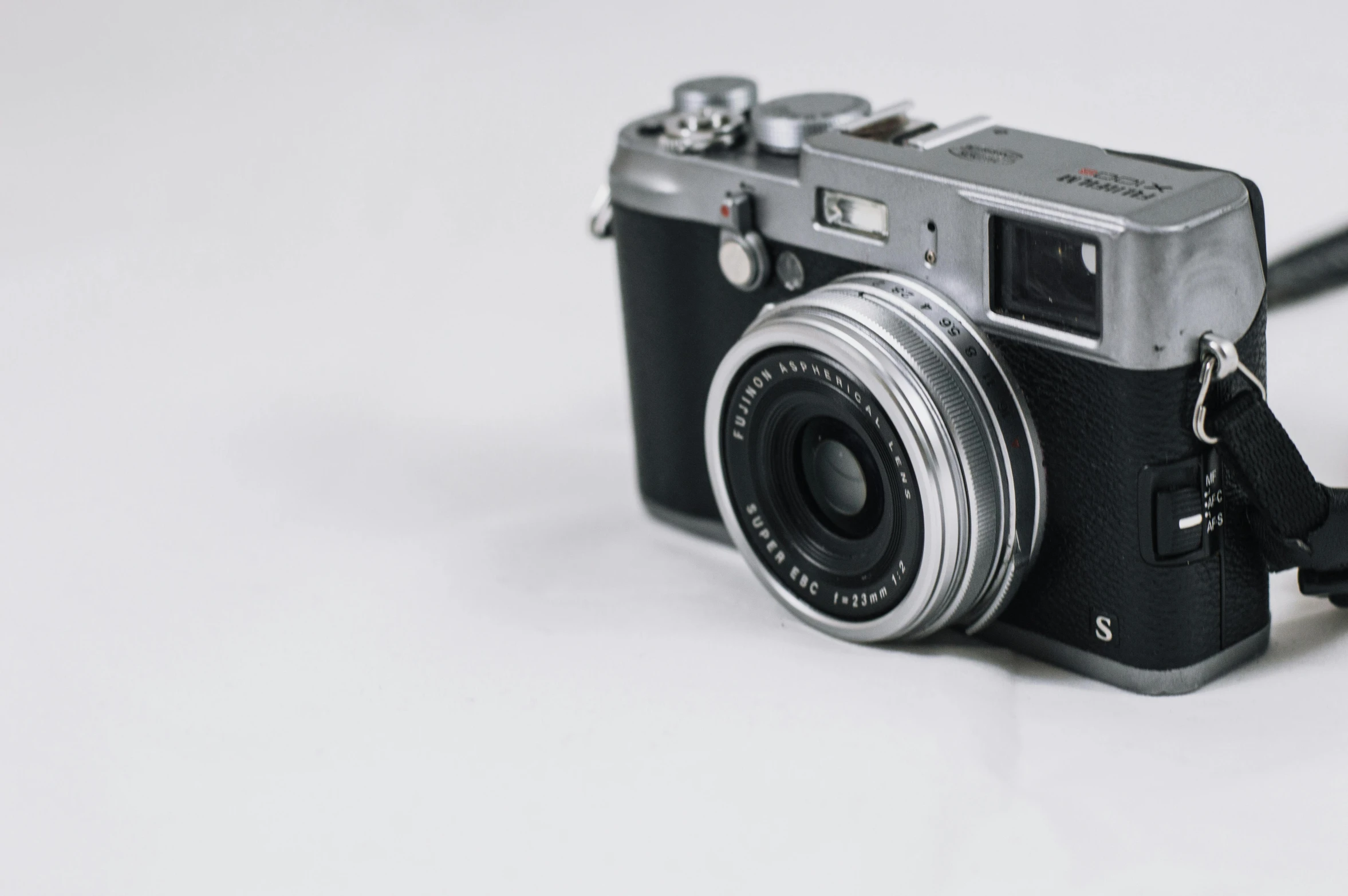 a black and silver camera on a white surface, unsplash contest winner, photorealism, fujifilm x100v, preserved historical, smooth.sharp focus, soft lens