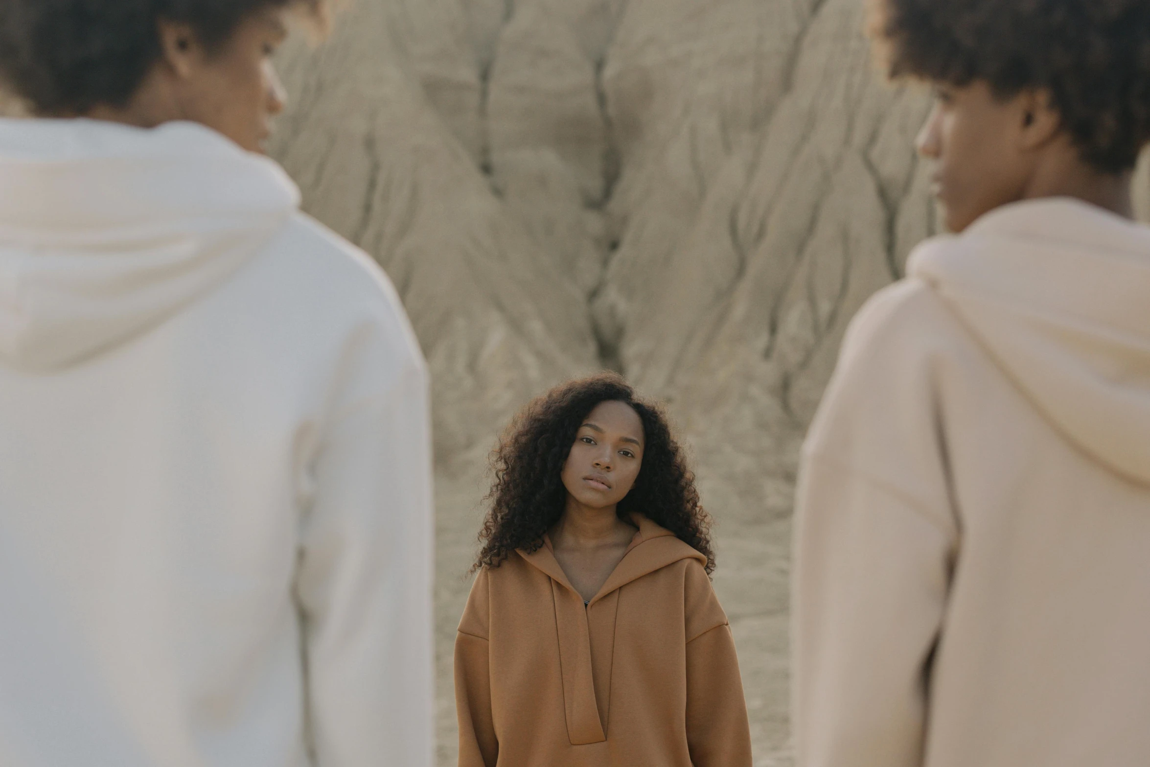 a couple of women standing next to each other, inspired by Vanessa Beecroft, trending on pexels, beige hoodie, in desert, three women, calmly conversing 8k