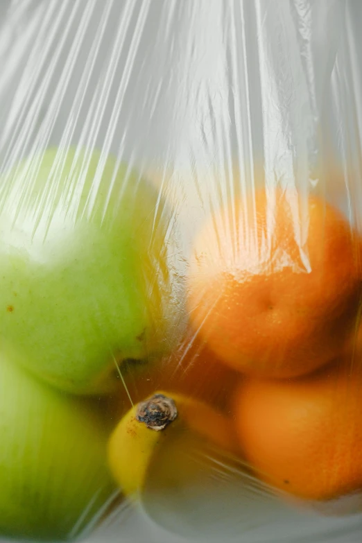 a plastic bag filled with oranges and apples, crisp lines, close together, photographic still, uncrop