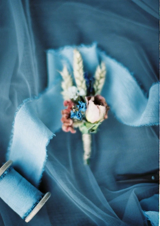 a close up of a flower on a blue cloth, wearing a light blue suit, chiffon, rich color palette, ((blue))