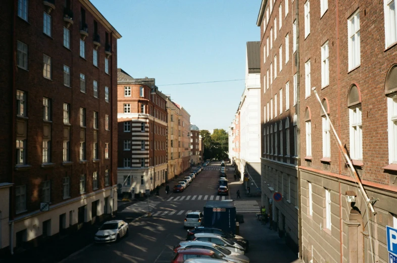 a city street filled with lots of parked cars, a picture, by Sigrid Hjertén, unsplash, hurufiyya, alvar aalto, dappled afternoon sunlight, tenement buildings, exterior view