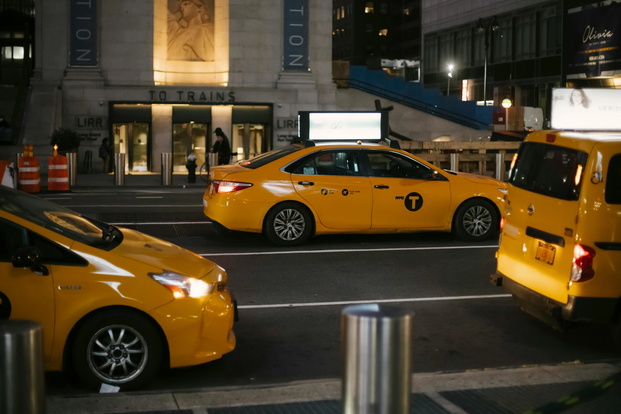 a couple of yellow taxis driving down a street, madison square garden, shot on sony a 7 iii, reflecting, an elegant