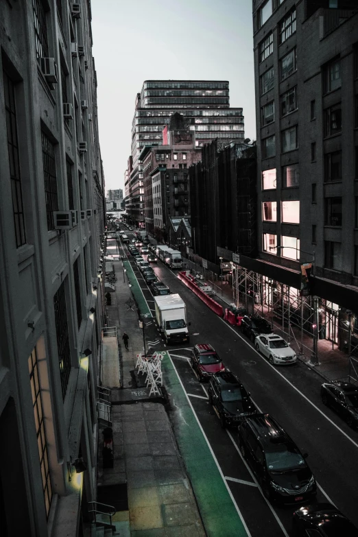 a city street filled with lots of traffic next to tall buildings, inspired by Thomas Struth, unsplash contest winner, dark alleyway, trending on vsco, new york buildings, late summer evening