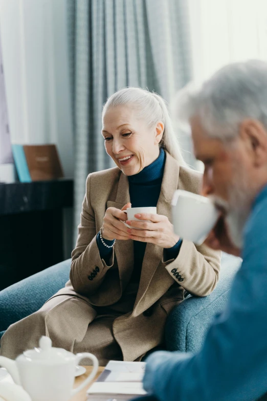 a man and a woman sitting on a couch in a living room, pexels contest winner, white haired lady, drinking a cup of coffee, professional photo, having a snack