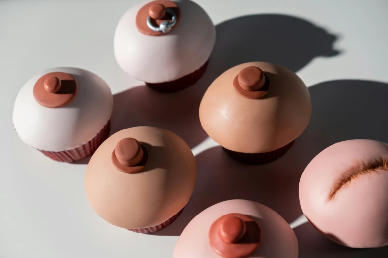 a group of cupcakes sitting on top of a table, inspired by Douglas Bourgeois, bauhaus, clay material, knobs, with soft pink colors, intimate holding close