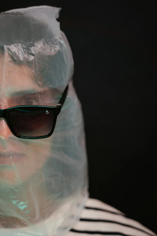 a woman wearing a plastic bag over her head, an album cover, inspired by Elsa Bleda, plasticien, wear ray - ban glass, photographed for reuters, vfx film closeup, protective