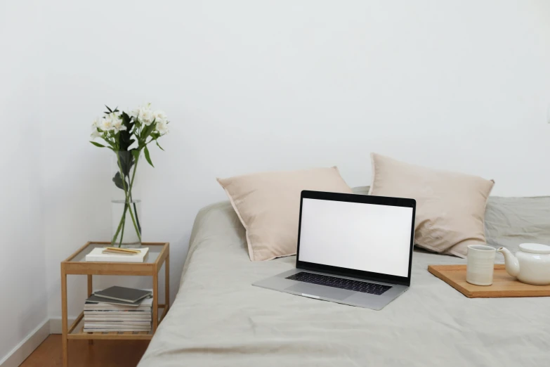 a laptop computer sitting on top of a bed, pexels, light beige pillows, sterile minimalistic room, 9 9 designs, no text