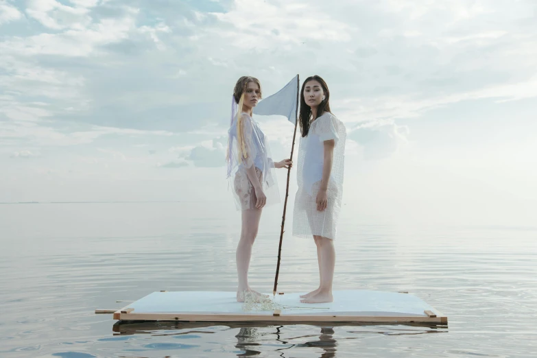 two women standing on a floating platform in the water, by Attila Meszlenyi, unsplash, conceptual art, holding a white flag, midsommar - t, uniform off - white sky, cardboard