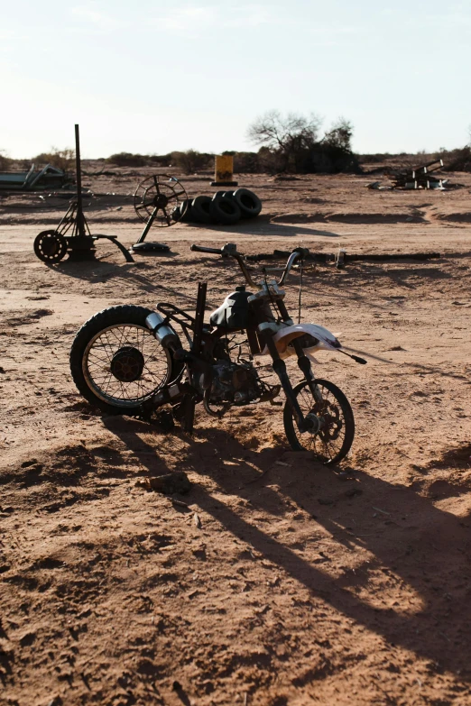 a dirt bike sitting on top of a sandy field, auto-destructive art, tools and junk on the ground, tuareg, on display, uncropped