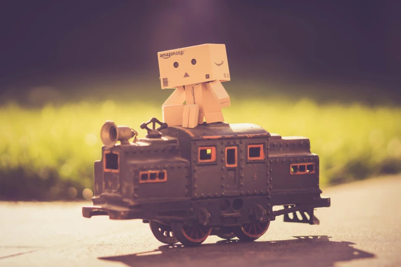 a toy of a robot sitting on top of a train, a picture, inspired by Jean Tabaud, unsplash, cardboard, vintage photo, avatar image, tan