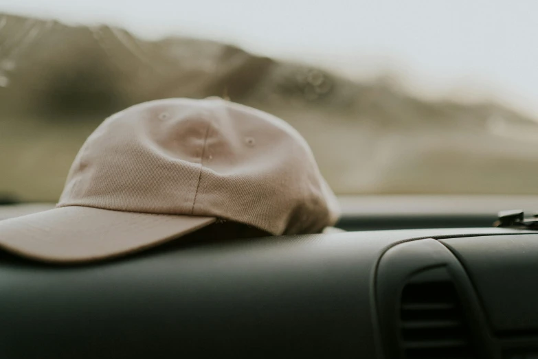 a baseball cap sitting on the dashboard of a car, trending on pexels, brown clothes, wearing nothing, headspace, thumbnail