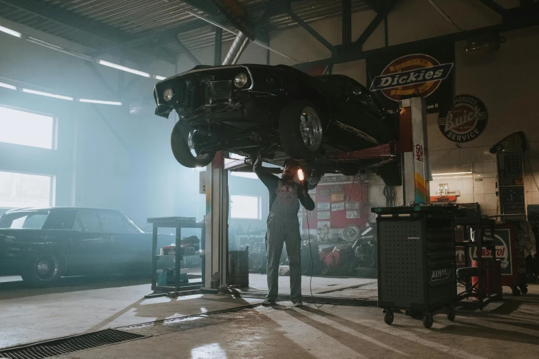 a man working on a car in a garage, by Daniel Lieske, pexels contest winner, 2 0 2 1 cinematic 4 k framegrab, moody hazy lighting, knight rider, car jumping