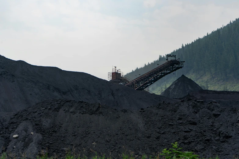 a large pile of dirt sitting on top of a lush green hillside, coal, background image, conveyor belts, profile image