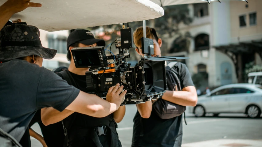 a group of people standing around a camera, action film, close to the camera, cinematográfica, tv production