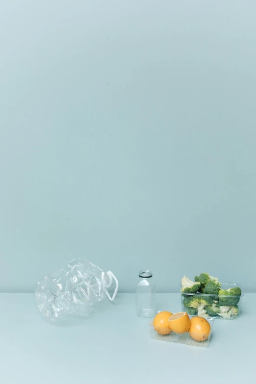 a couple of oranges sitting on top of a table, a still life, pexels contest winner, minimalism, plastic bottles, veggies, light-blue, grey