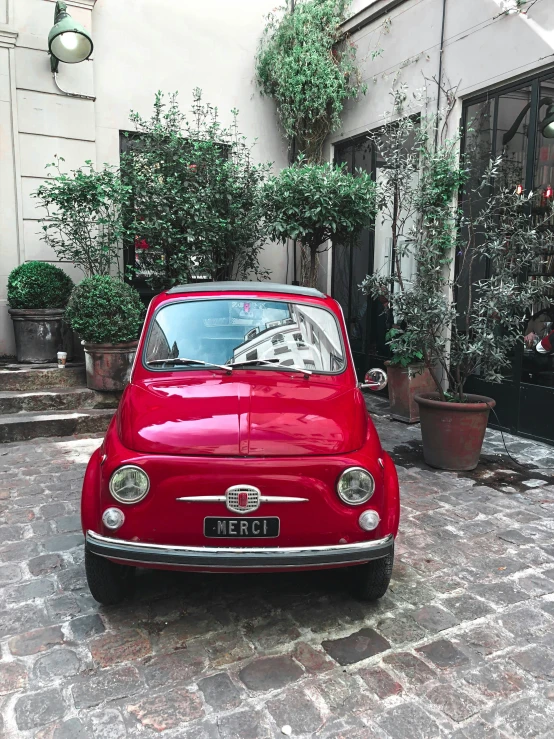 a small red car parked on a cobblestone street, 💋 💄 👠 👗, michaelangelo style, delightful surroundings, filled with natural light