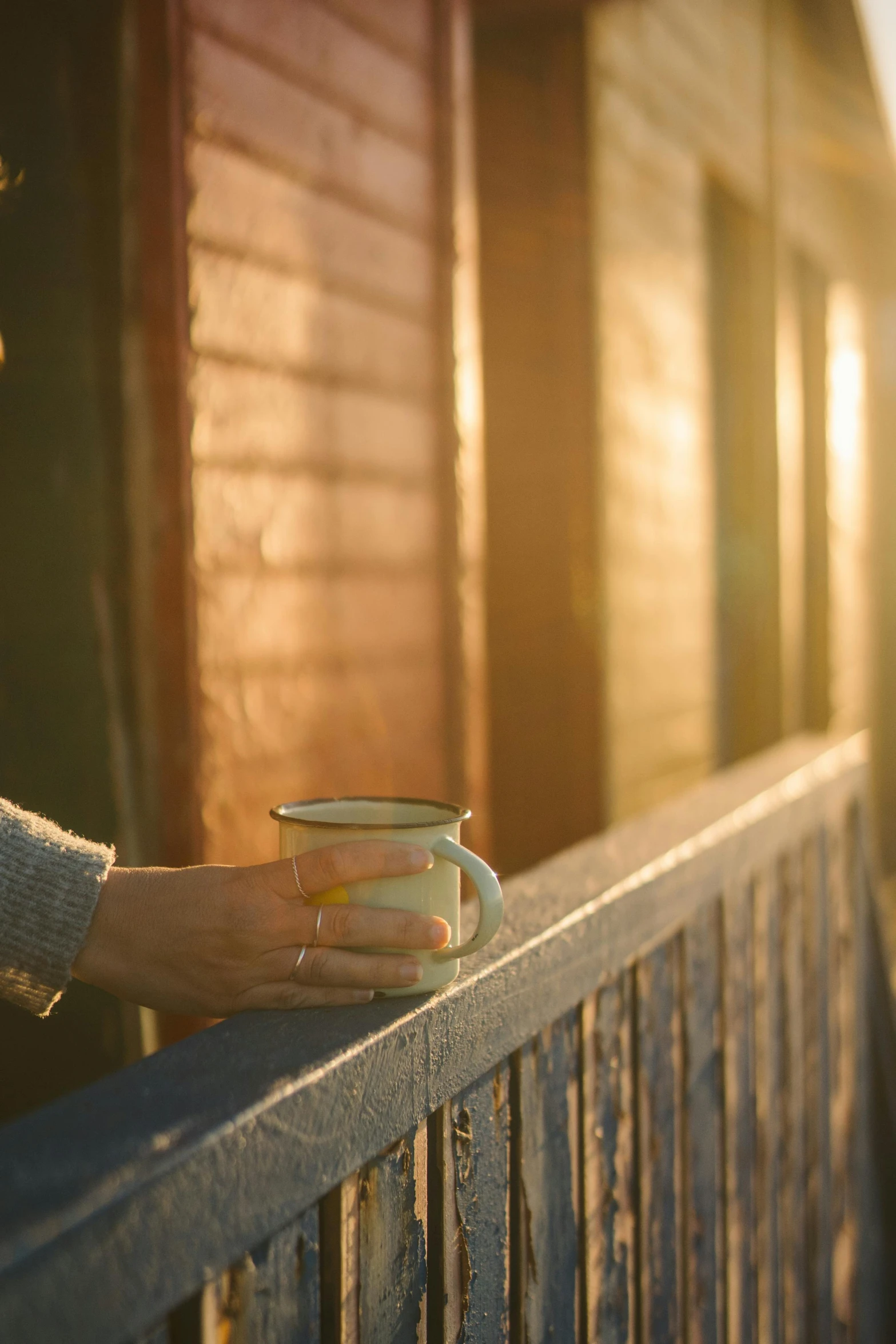 a woman holding a cup of coffee on a balcony, by David Simpson, pexels, dramatic warm morning light, stood outside a wooden cabin, archviz, morning detail