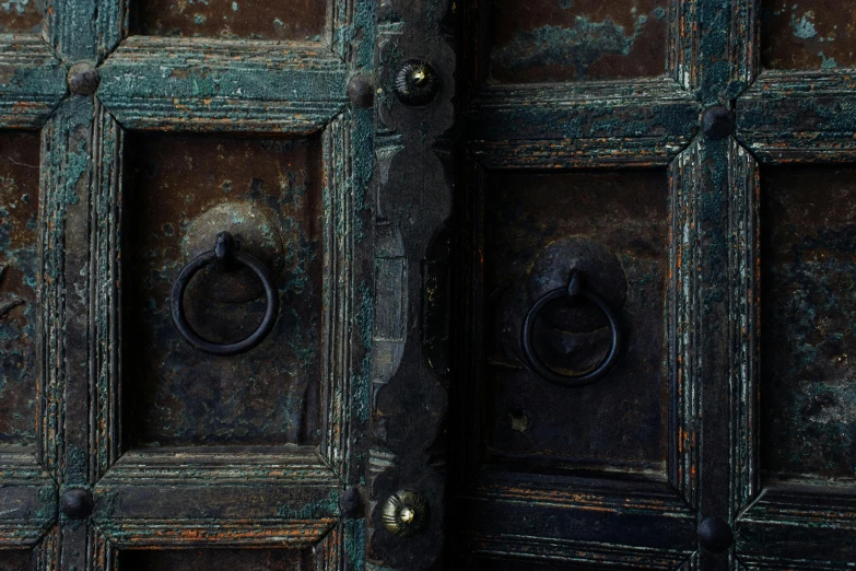 a close up of a door handle on a wooden door, an album cover, by Elsa Bleda, pexels contest winner, renaissance, copper and emerald, made of wrought iron, 3 doors, middle eastern details