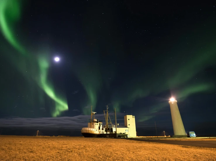 a large ship sitting on top of a dry grass field, by Hallsteinn Sigurðsson, pexels contest winner, northern lights in space, light house, square, two moons lighting