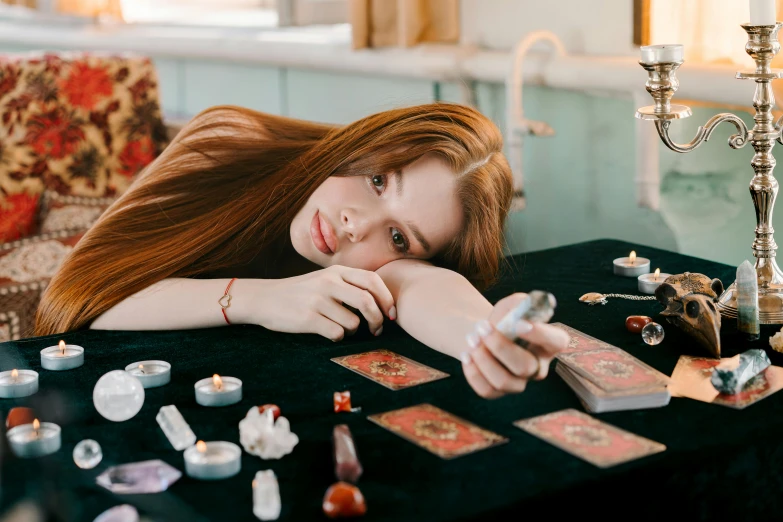 a woman that is laying down on a table, by Julia Pishtar, trending on pexels, renaissance, tarot cards characters, long ginger hair, the woman holds more toys, with crystals on the walls