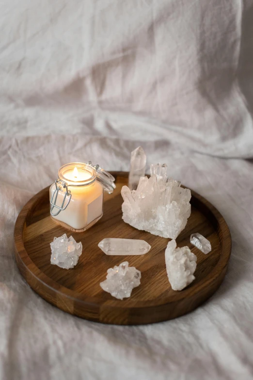 a candle sitting on top of a wooden tray, a still life, by Jessie Algie, trending on pexels, made of crystals, white light, lumi, close together