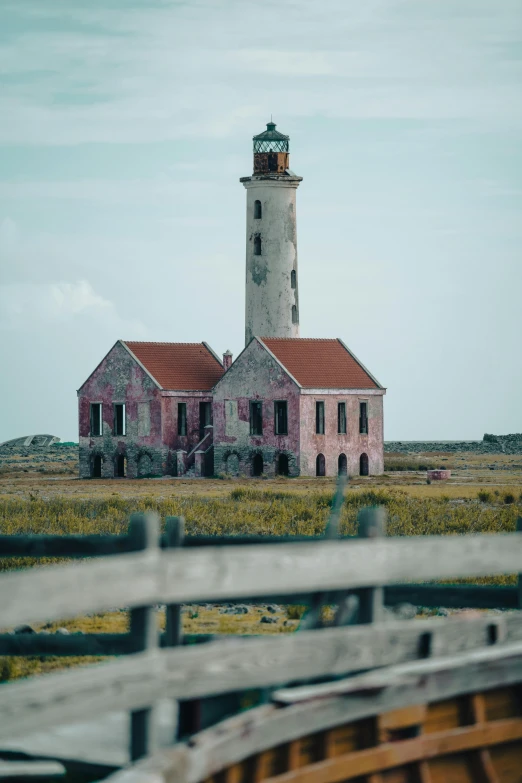 a pink house sitting in the middle of a field, a colorized photo, by Jan Tengnagel, pexels contest winner, lighthouse, aruba, old building, rustic