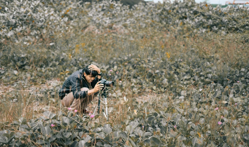 a man taking a picture of a field with a camera, by Carey Morris, unsplash, art photography, amongst foliage, digging, medium format, film still