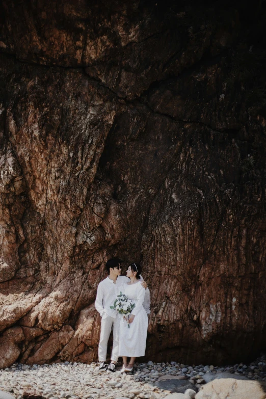 a man and a woman standing in front of a rock, by Tan Ting-pho, unsplash, romanticism, bride and groom, in style of lam manh, color”