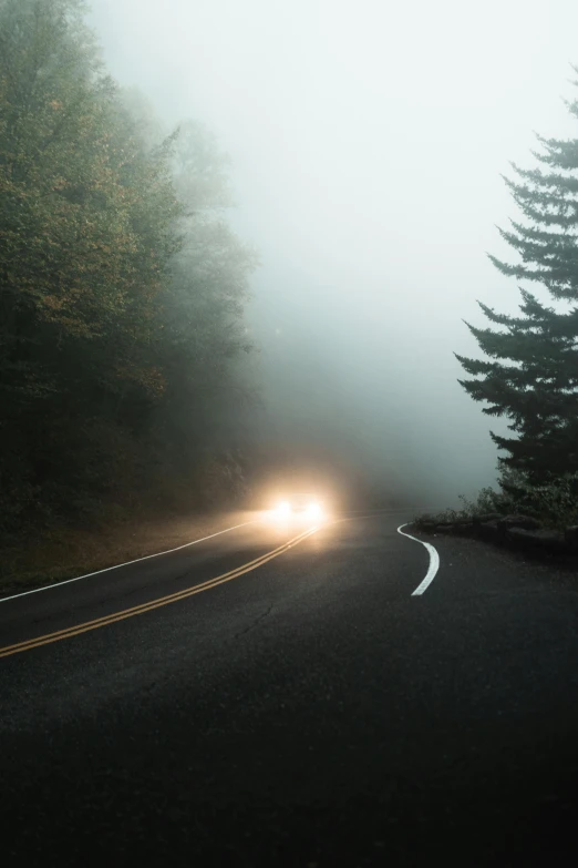 a car driving down the road on a foggy day, inspired by Elsa Bleda, unsplash contest winner, pacific northwest, with cool headlights, 2019 trending photo, 'silent hill '