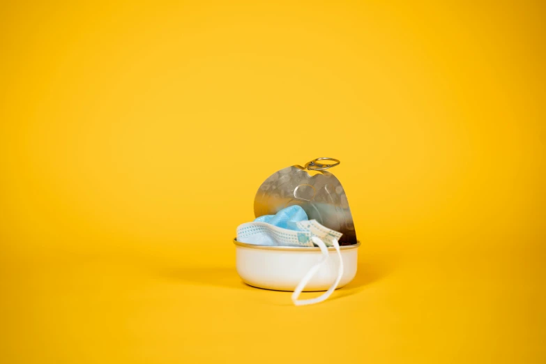a pair of shoes and a bag of trash on a yellow background, a still life, by Emma Andijewska, conceptual art, metal lid, face mask, nursing, soup