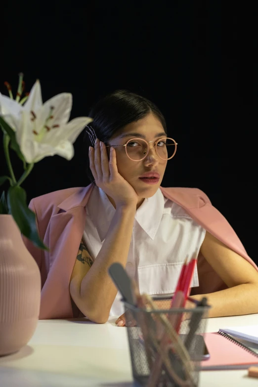 a woman sitting at a table in front of a laptop computer, an album cover, trending on pexels, hyperrealism, mia khalifa, androgynous person, woman with rose tinted glasses, asian woman