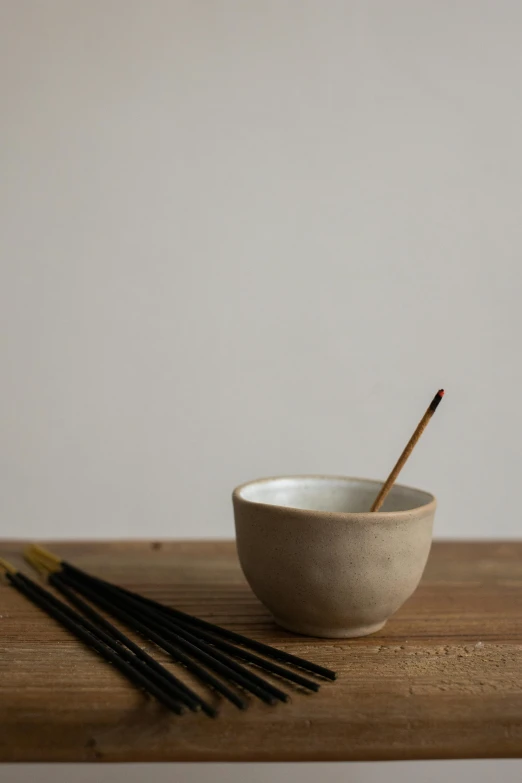 a white bowl sitting on top of a wooden table, a still life, unsplash, mingei, incense, grey, made of glazed, small