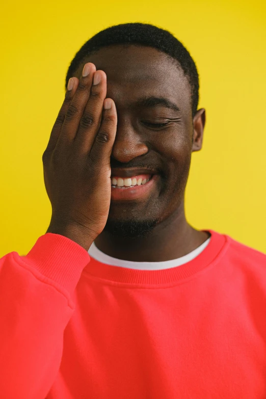 a man covering his eyes with his hands, an album cover, by Stokely Webster, trending on pexels, wearing red and yellow clothes, smiling laughing, mkbhd, headshot profile picture