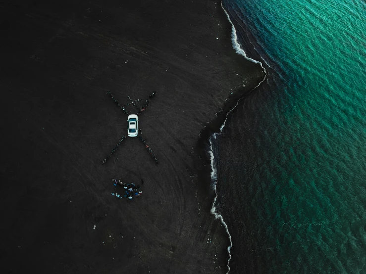 a boat sitting on top of a beach next to the ocean, by Jesper Knudsen, pexels contest winner, black car, taken from a plane, people on the ground, iceland