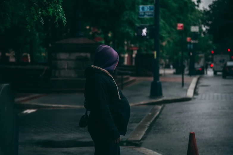 a person standing on a street corner in the rain, pregnant belly, young man in a purple hoodie, unsplash photography, long night cap