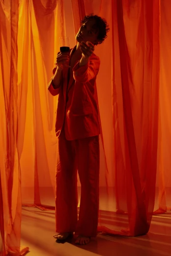 a man standing in front of a red curtain, inspired by Georges de La Tour, pexels contest winner, orange jumpsuit, showstudio, ( ( theatrical ) ), ethereal curtain