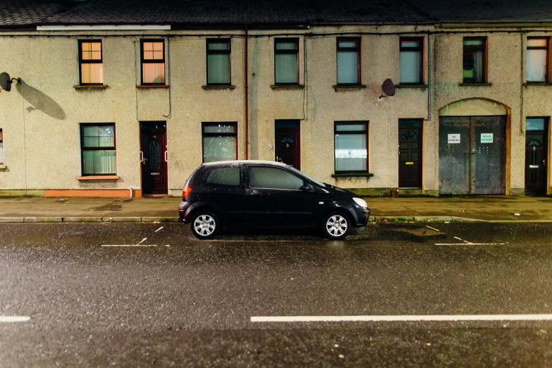 a small black car parked in front of a building, by Eamon Everall, photograph of the year, standing in a township street, conor walton, thumbnail