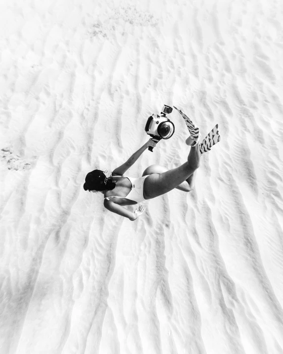 a black and white photo of a person laying in the sand, soccer ball against her foot, drone photograpghy, female ascending into the sky, instagram model