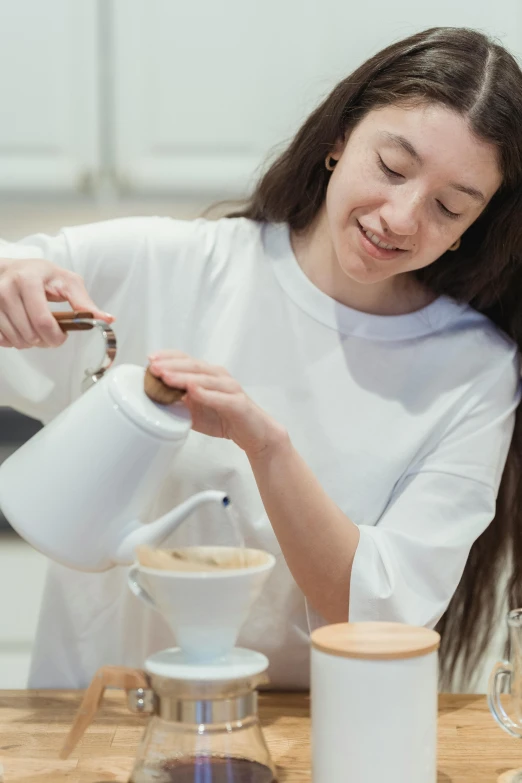 a woman is pouring a cup of coffee, by Julia Pishtar, lachlan bailey, profile image, white apron, college