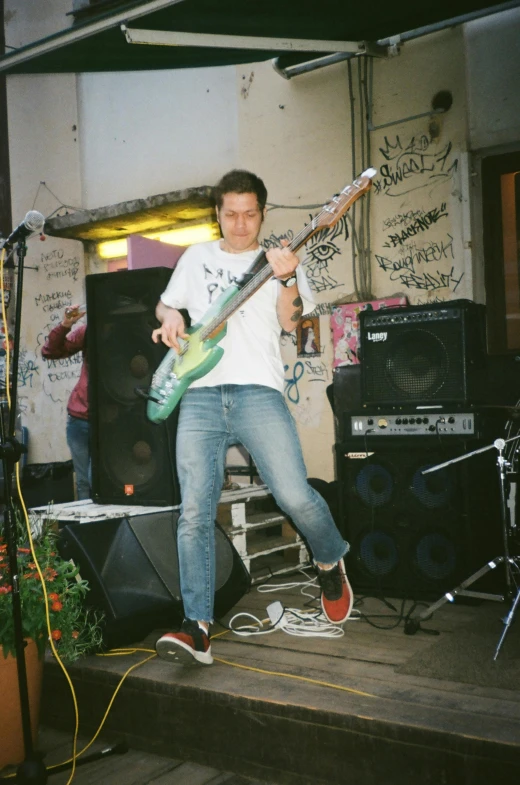 a man standing on a stage with a guitar, an album cover, unsplash, happening, mosh pit, 1990's photo, in tokio, in house