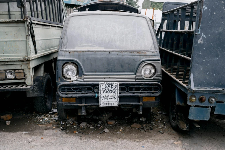 a couple of trucks parked next to each other, an album cover, unsplash, mingei, many scrap cars, front view 2 0 0 0, tehran, grey metal body