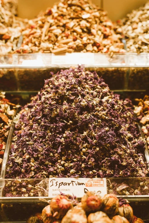 a display case filled with lots of different types of nuts, by Julia Pishtar, black and purple rose petals, basil, cone shaped, market in ancient rome