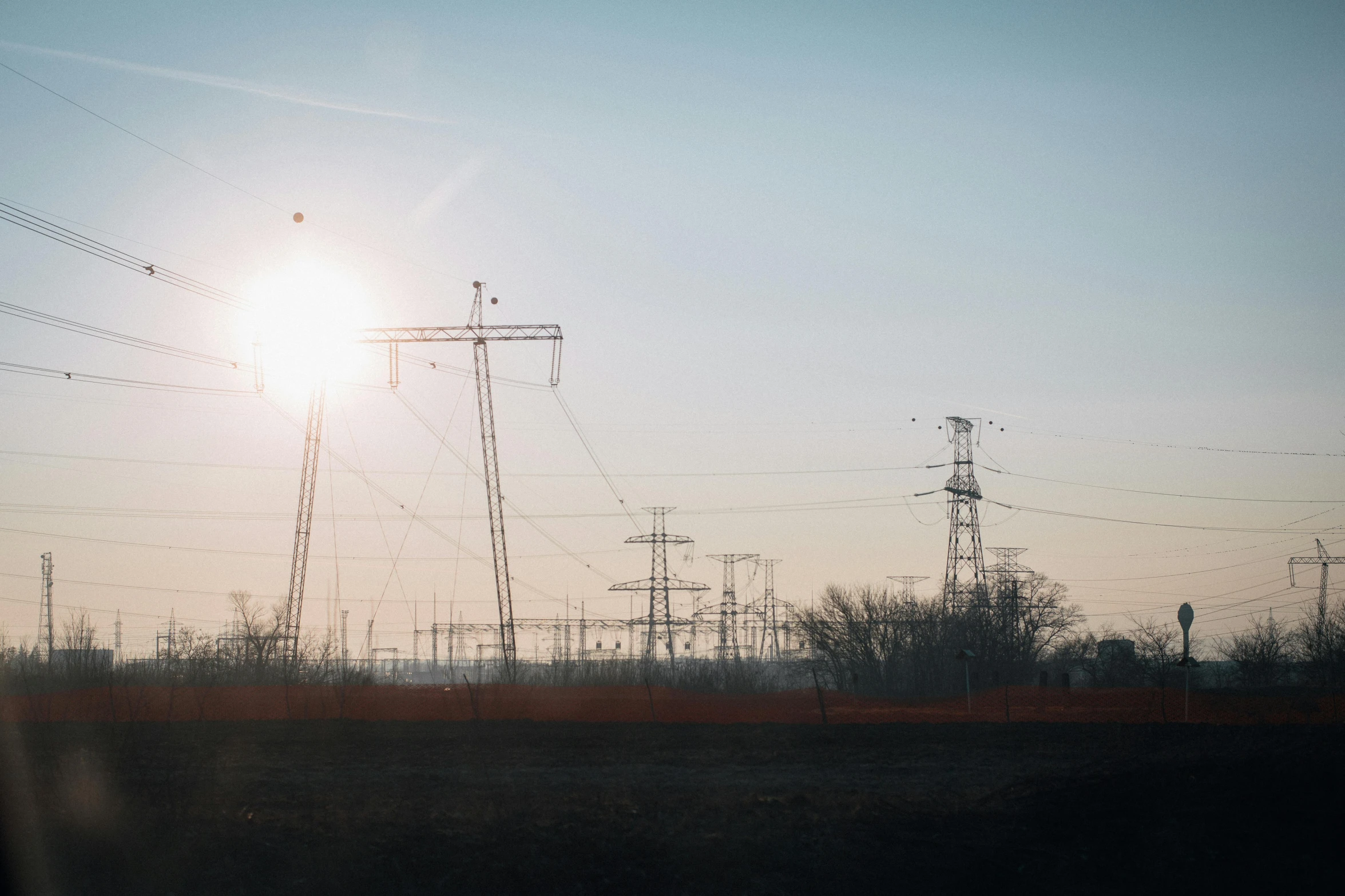 the sun is setting behind power lines, a picture, by Adam Marczyński, pexels contest winner, renaissance, light source from the left, bright sunny day, large scale photo, tall metal towers