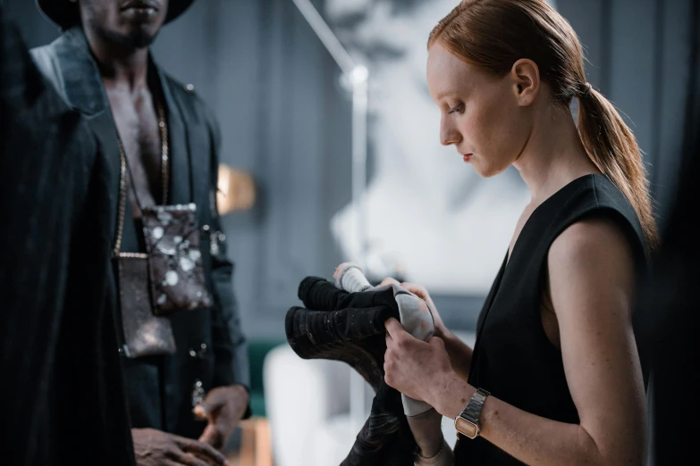 a woman in a black dress holding a camera, eleanor tomlinson, inspect in inventory image, leather clothing and boots, raphael personnaz