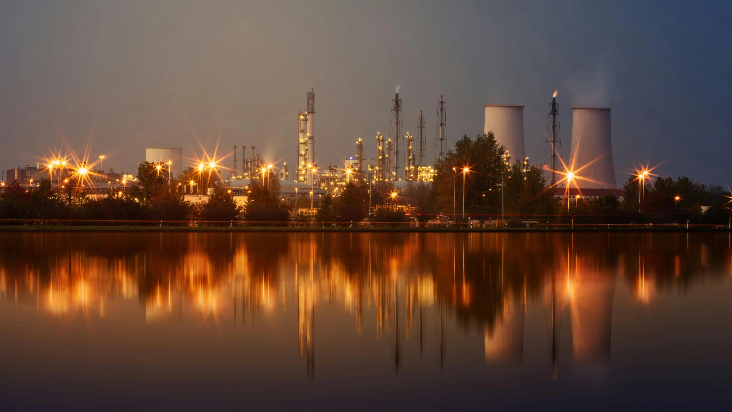 an oil refinery at night reflected in the water, pexels contest winner, photorealism, instagram post, ilustration, hazy atmosphere, landscape photo-imagery