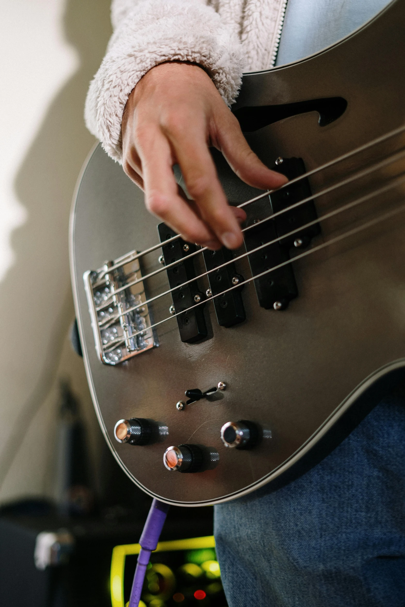 a close up of a person playing a bass guitar, grey and silver, at home, zoomed in, rectangle