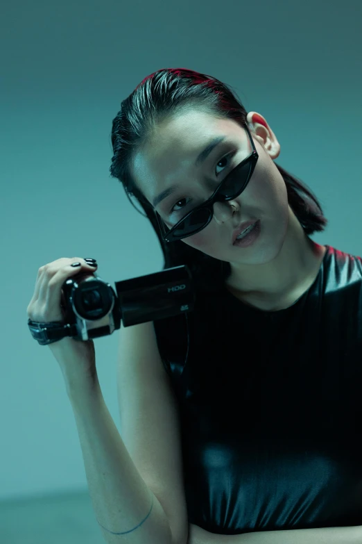 a woman in a black top holding a camera, inspired by Zhu Da, wearing futuristic clothing, reflective lens, siwoo kim, reflective sunglasses