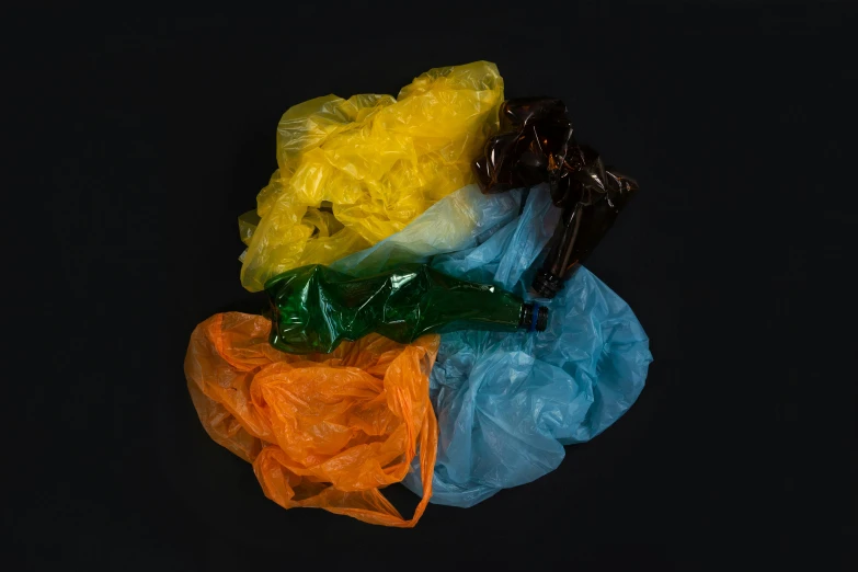 a bunch of plastic bags sitting on top of a table, 5 colors, on a black background, some orange and blue, ignant